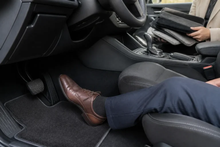 bestuurder met nette schoenen op een velours automat bij de pedalen terwijl passagier matstalen vergelijkt